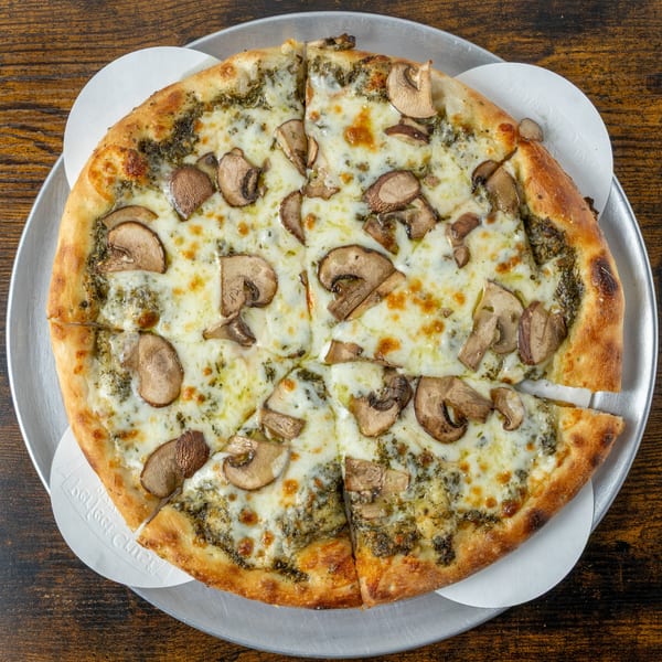 Oak Pantry Deli n' Pizza's mushroom and pesto pizza, cut into slices on a metal tray.