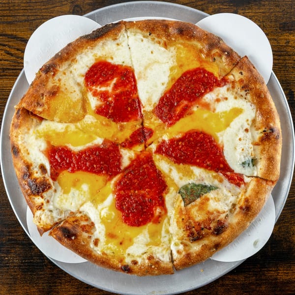 A sliced Oak Pantry Deli n' Pizza pie with red sauce, white and yellow cheese, on a metal tray.